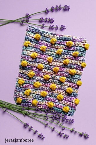 a bobble crochet book sleeve is surrounded by stalks of lavender